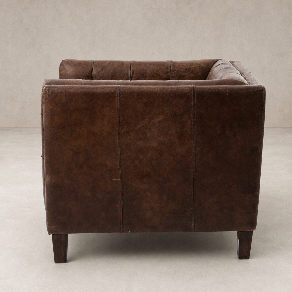 Venice Club Chair in cigar leather, showcasing a sleek, modern silhouette with sturdy wooden legs.