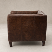 Venice Club Chair in cigar leather, showcasing a sleek, modern silhouette with sturdy wooden legs.