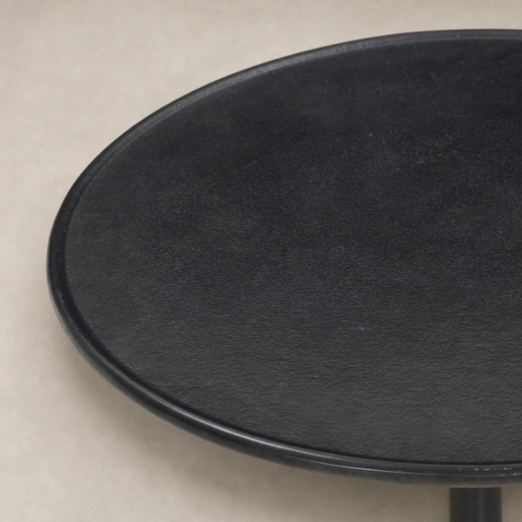 Calder Matchstick Pedestal Table features a sleek, round black surface and minimalist design.