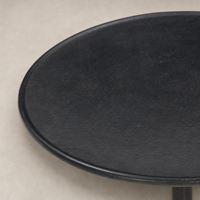 Calder Matchstick Pedestal Table features a sleek, round black surface and minimalist design.
