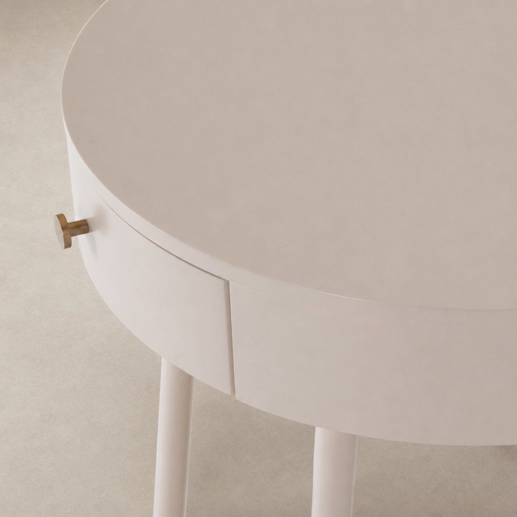 Finn Nightstand in soft pink features a round top and sleek legs with a gold handle.