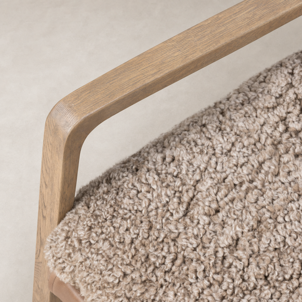 Close-up of the taupe shearling seat and wooden armrest of the Sawyer Chair.