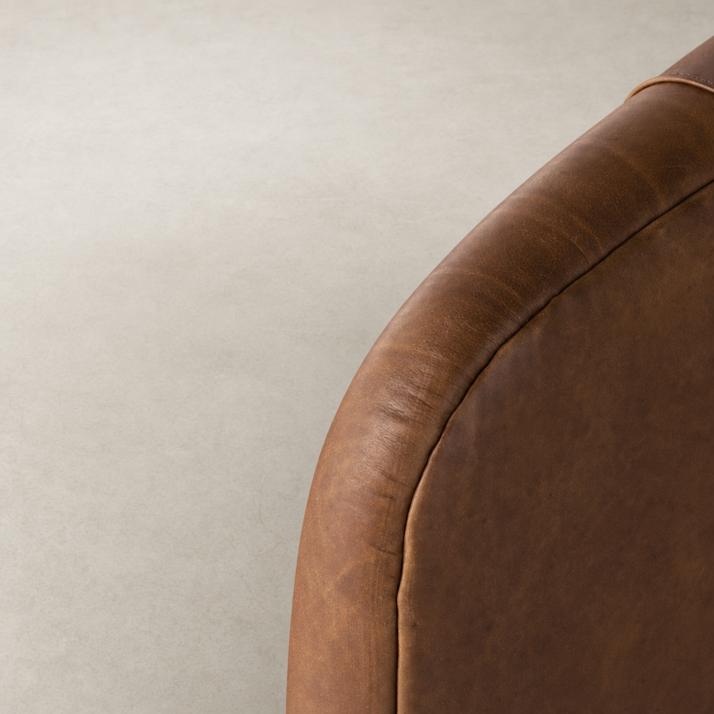Heirloom Sienna Magnolia Swivel Chair showing rich, textured leather detail and curved edge.