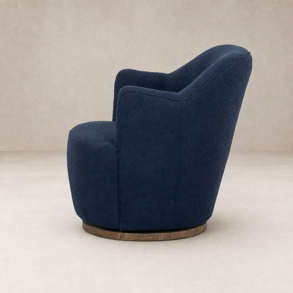 Soliel Swivel Chair in Copenhagen Indigo with a rounded, plush design and wooden base.