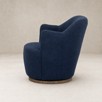 Soliel Swivel Chair in Copenhagen Indigo with a rounded, plush design and wooden base.