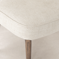 Orson Dining Chair in Cambric Ivory, showcasing a textured fabric seat and wooden legs.