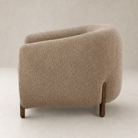Clover Chair in sheepskin camel features a rounded shape and wooden legs.