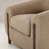 Clover Chair featuring cozy sheepskin camel upholstery and sleek wooden legs.