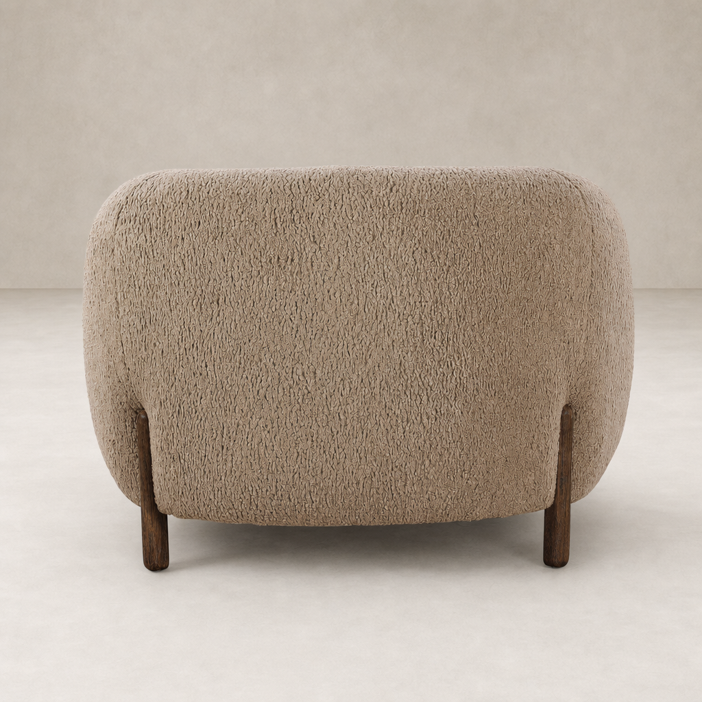 Clover Chair inSheepskin Camel features a rounded back and wooden legs.