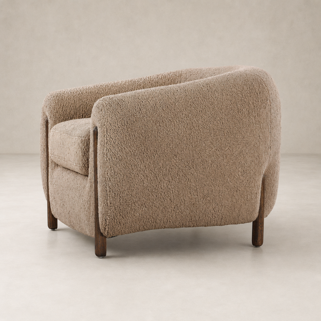 Clover Chair in Sheepskin Camel with rounded shape and wooden legs.