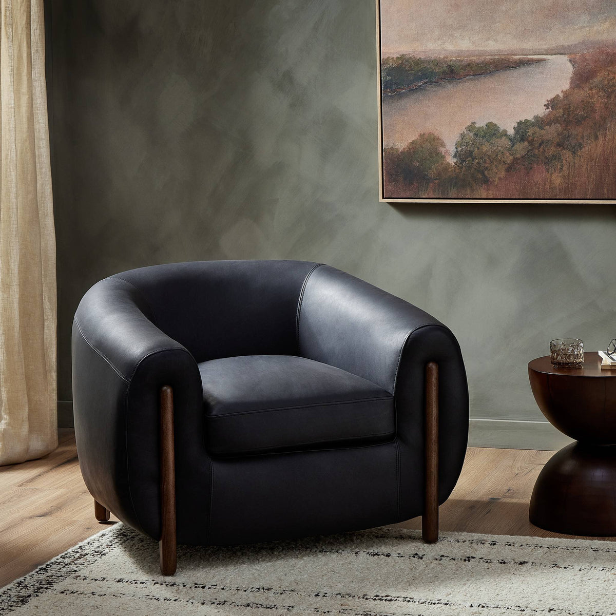 Clover Chair in Heirloom Black with rounded shape and wooden legs, styled in a cozy setting.