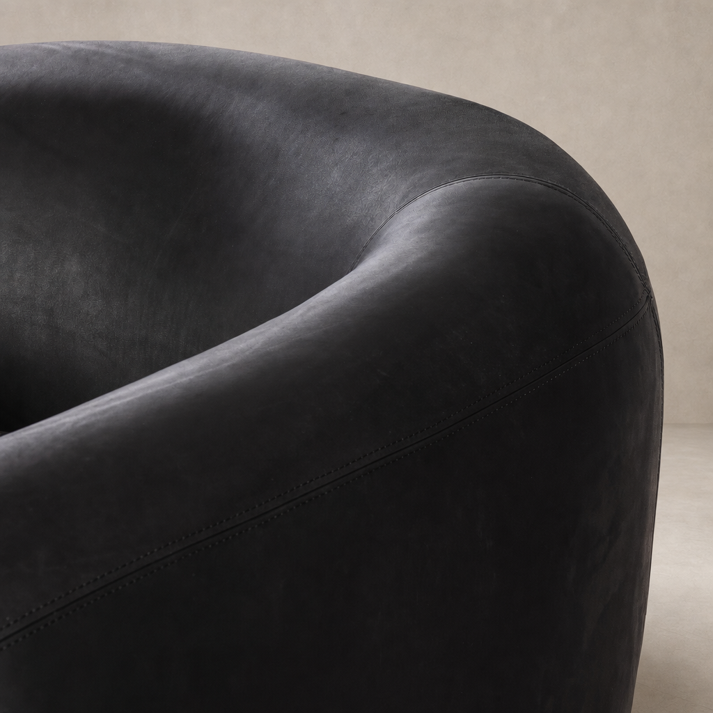 Clover Chair in Heirloom Black featuring a smooth, rounded design and subtle stitching details.