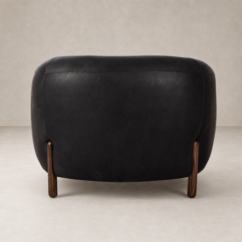 Curvy Clover Chair in heirloom black leather with wooden legs, showcased from the back.