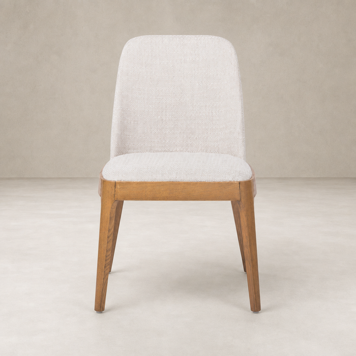 Rhys Armless Dining Chair in Gibson Wheat featuring a smooth upholstered seat and wooden legs.