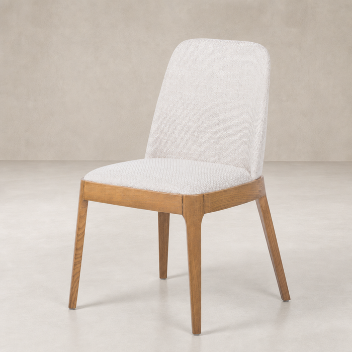 Rhys Armless Dining Chair in Gibson Wheat features a textured fabric seat and sleek wooden legs.