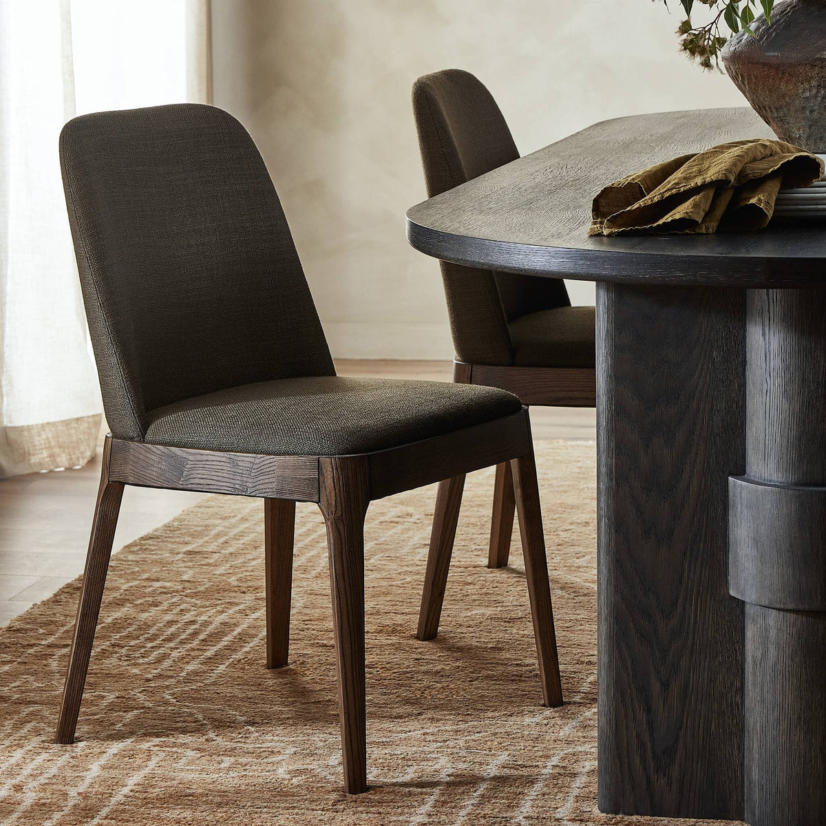 Rhys Armless Dining Chair in Bilton Olive with a sleek design and wooden legs.