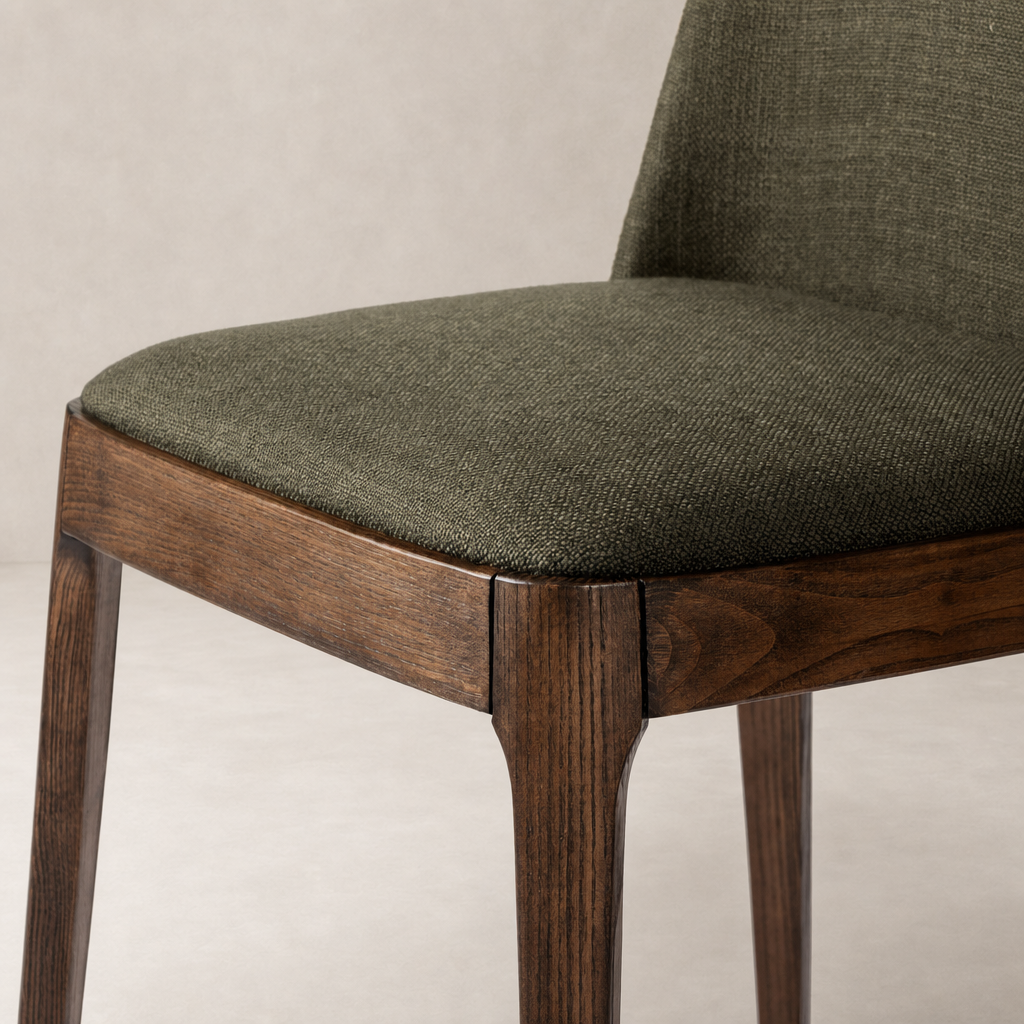 Rhys Armless Dining Chair in Bilton Olive with textured fabric seat and wooden legs.