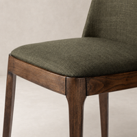 Rhys Armless Dining Chair in Bilton Olive with textured fabric seat and wooden legs.