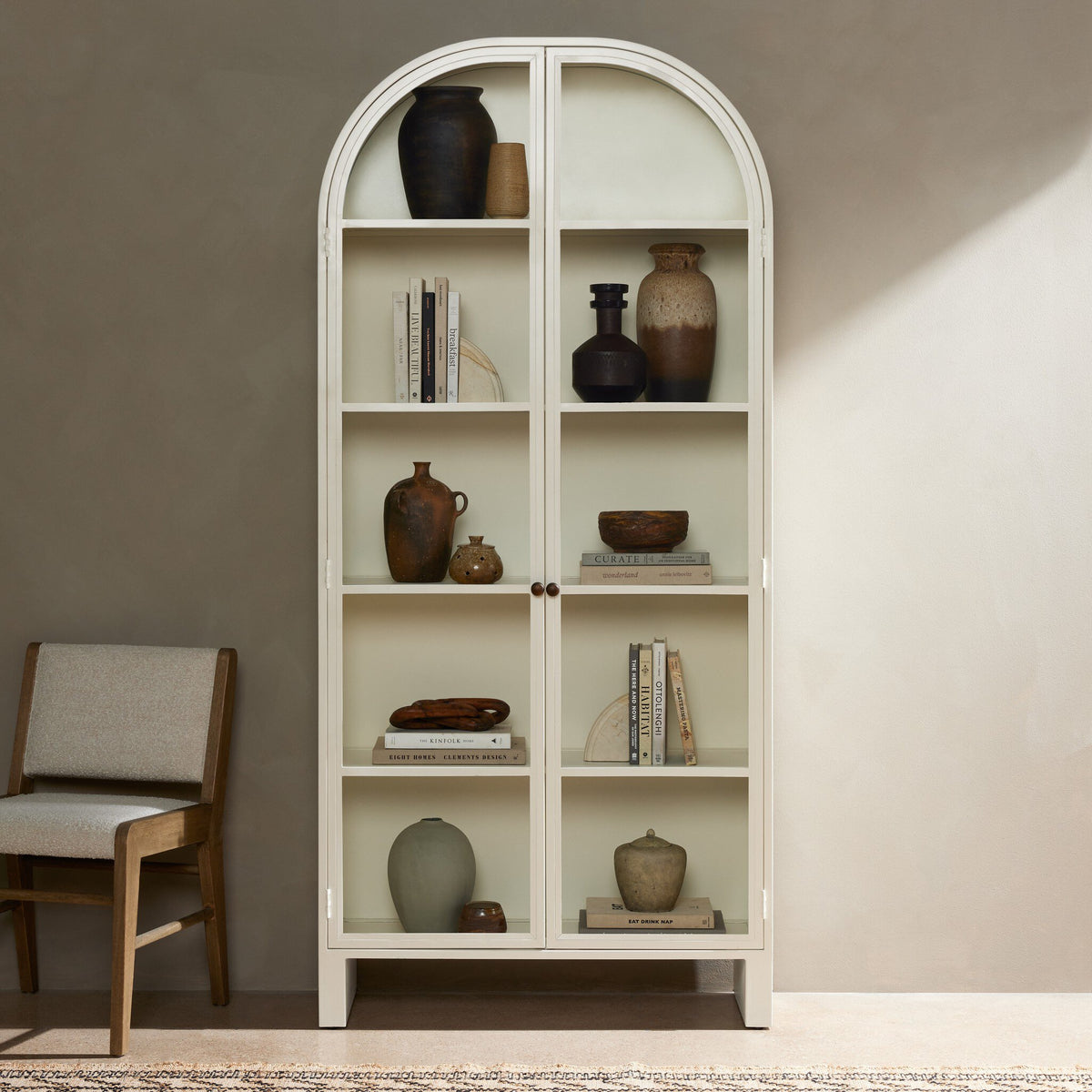 Cream powder coat Delta Cabinet featuring arched top and open shelving in a stylish room setting.
