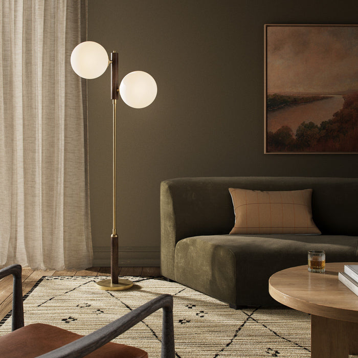Aged brass floor lamp with two globes, adding elegance to a cozy living room.