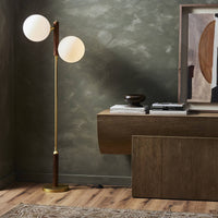 Aged brass floor lamp with two globe shades in a modern living room setting.