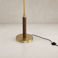 Aged brass floor lamp with a sleek wooden base and minimalist design.