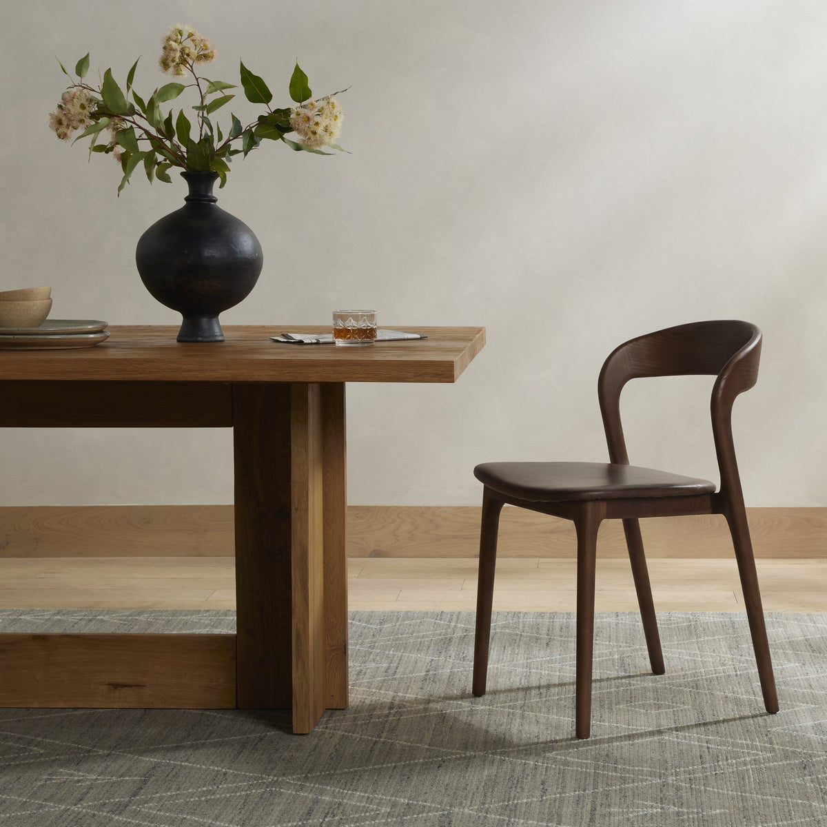 Amato Dining Chair in Sonoma Coco with smooth contours beside a wooden dining table.