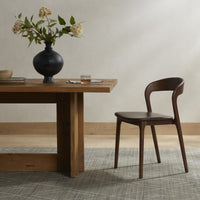 Amato Dining Chair in Sonoma Coco with smooth contours beside a wooden dining table.