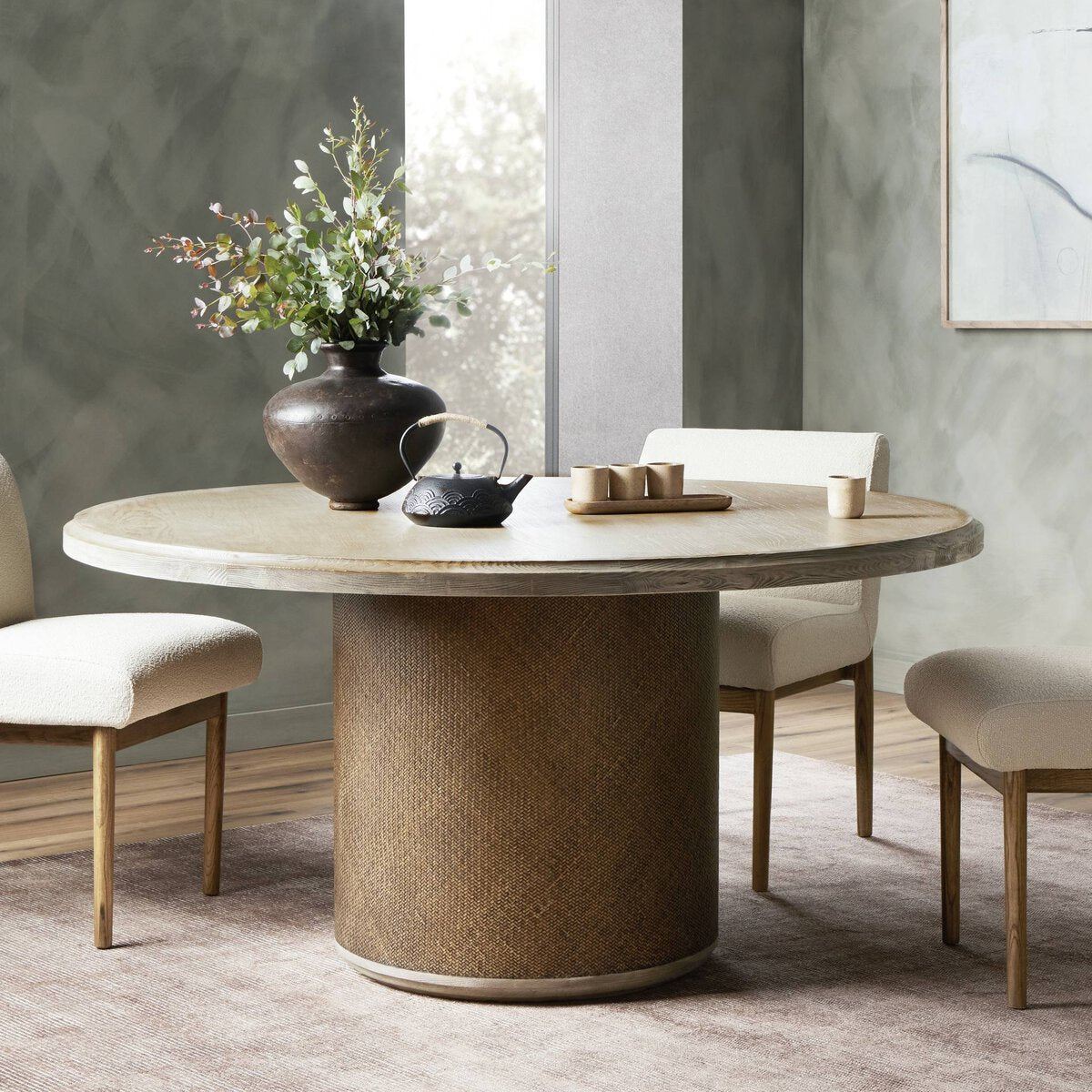 Close-up of the Kaia Round Dining Table, featuring a natural wood top and textured cylindrical base.