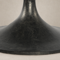 Close-up of the Sabine Round Coffee Table's raw black textured base.