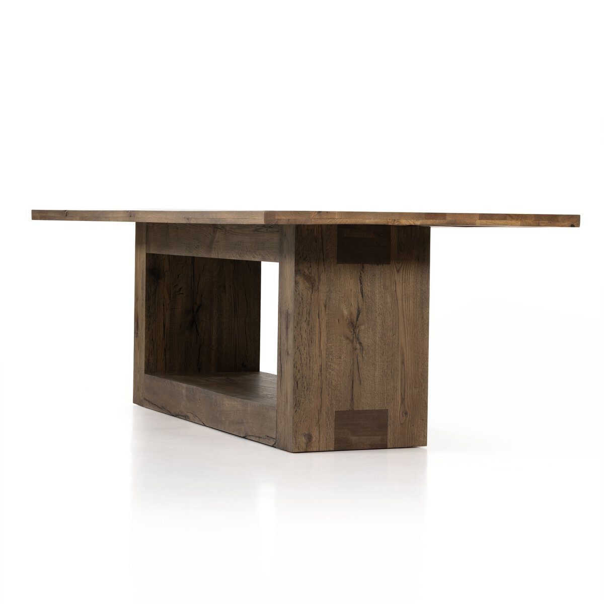 Three-quarter view of the Thalia Dining Table, showcasing its rustic finish and unique base design.