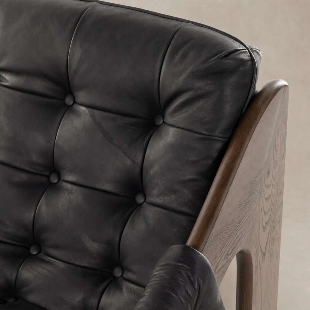 Langston Chair in Heirloom Black featuring tufted leather and a wood armrest.