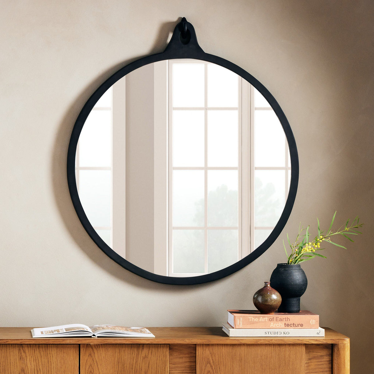 Knox Round Mirror featuring a sleek black aluminum frame, elegantly displayed above a wooden console.