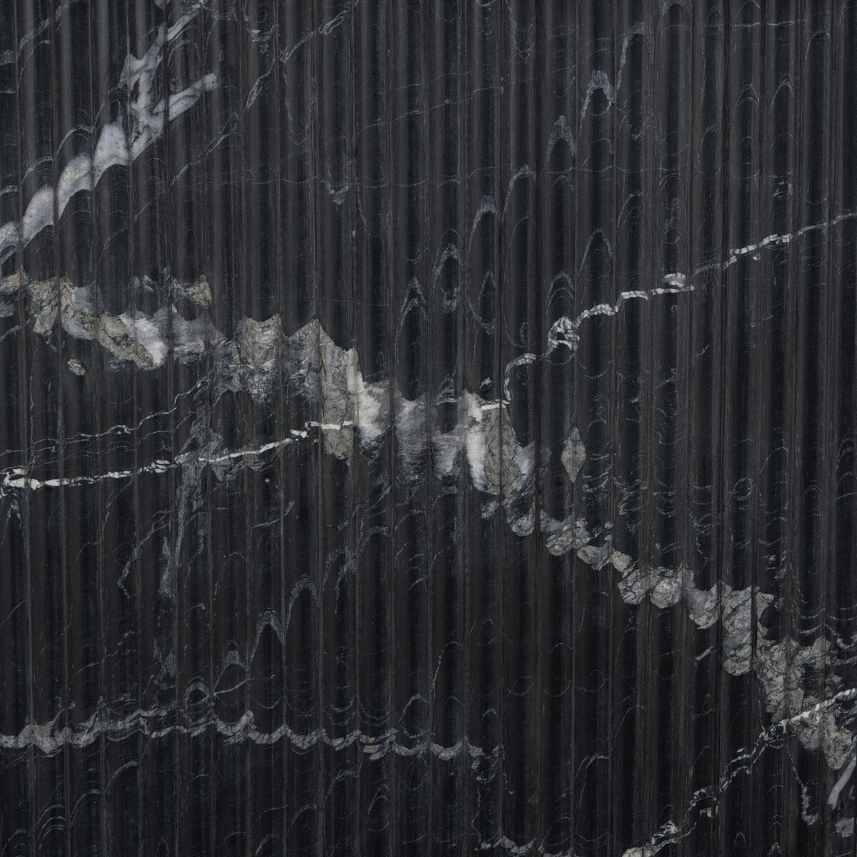 Detail of the Elysia Dining Table's textured black marble surface, showcasing elegant veining.