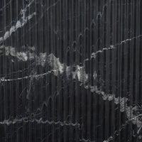 Detail of the Elysia Dining Table's textured black marble surface, showcasing elegant veining.