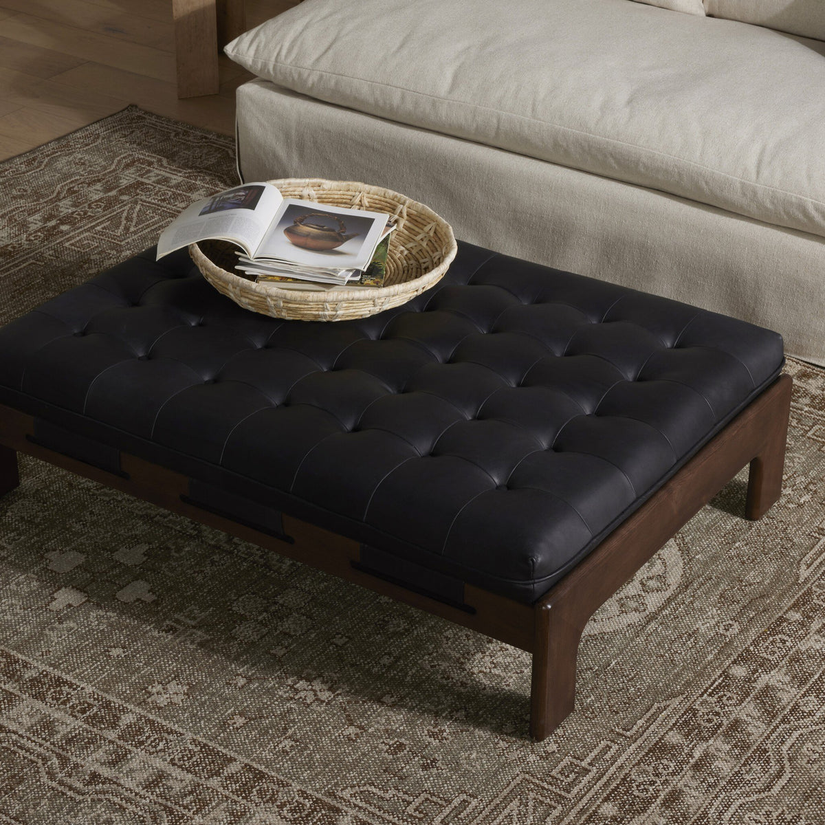 Hudson Cocktail Ottoman in heirloom black with tufted leather top and wooden legs.