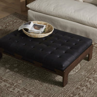 Hudson Cocktail Ottoman in heirloom black with tufted leather top and wooden legs.