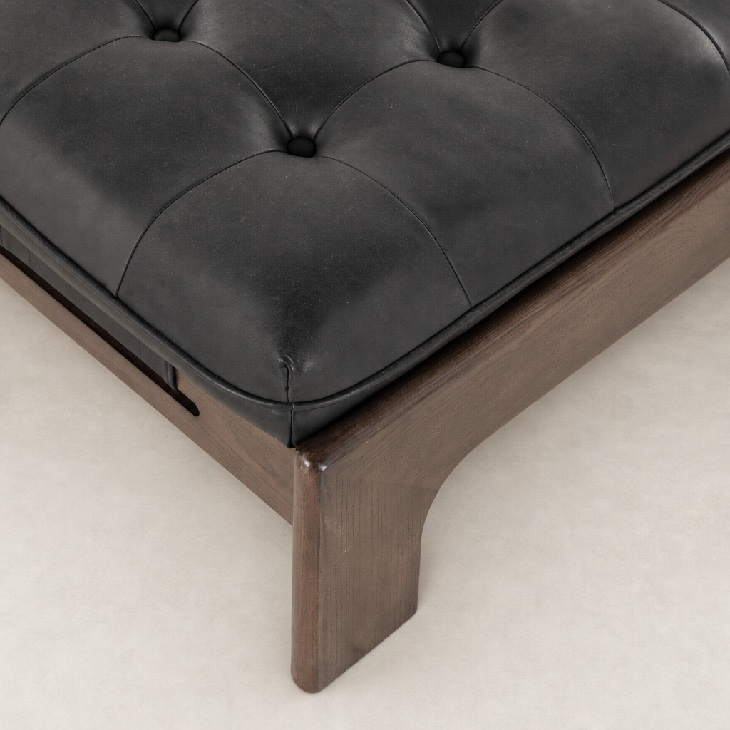 Hudson Cocktail Ottoman in Heirloom Black featuring a tufted leather cushion and sleek wooden base.