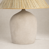 Sand porcelain table lamp with a rounded base and natural woven shade.
