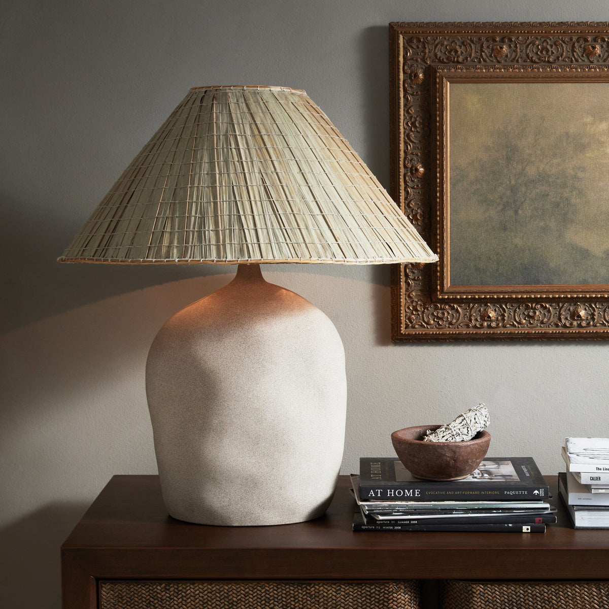 Sand porcelain table lamp with a textured base and woven shade, beautifully styled on a console.