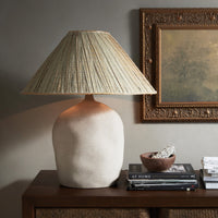 Sand porcelain table lamp with a textured base and woven shade, beautifully styled on a console.