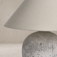Antique white ceramic table lamp with a textured base and tapered fabric shade.
