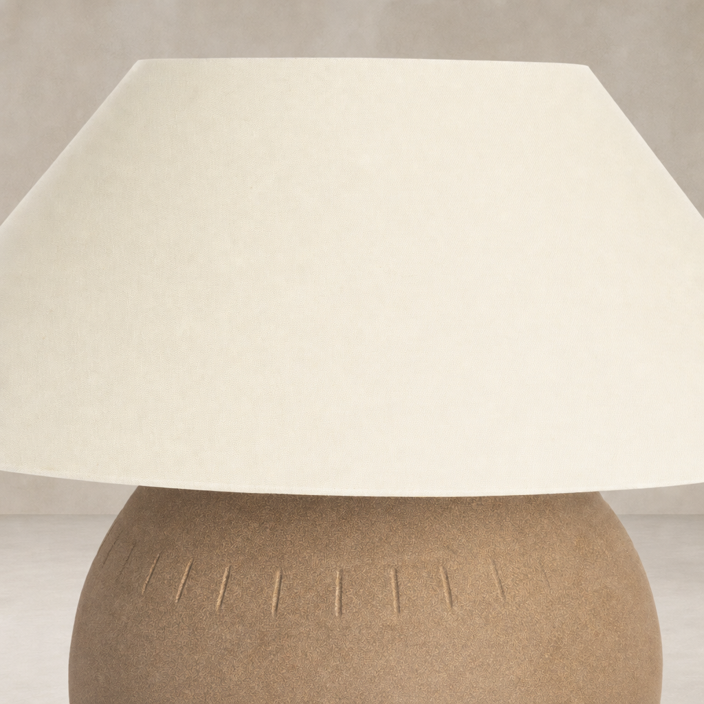 Dark sand porcelain ceramic table lamp with textured base and wide shade.