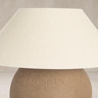 Dark sand porcelain ceramic table lamp with textured base and wide shade.
