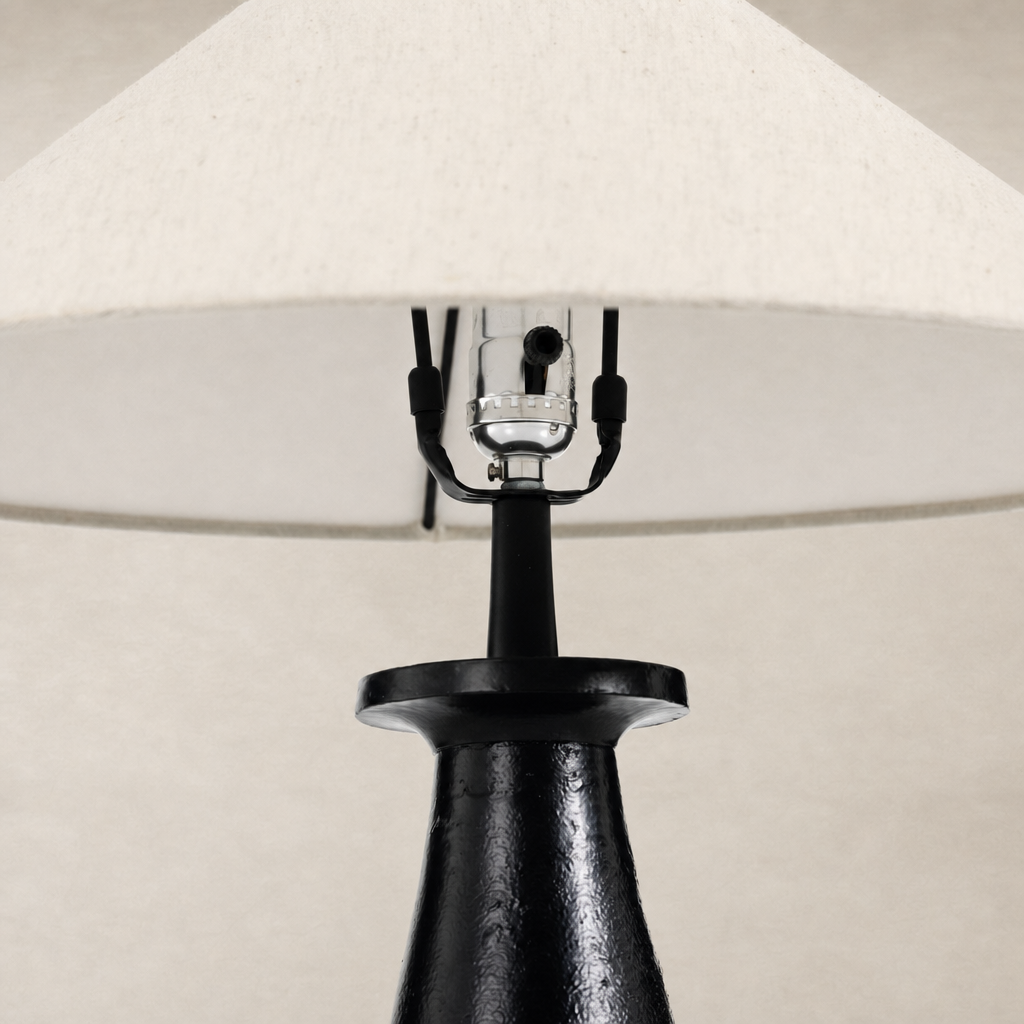 Matte black cast aluminum tapered shade table lamp with a fabric lampshade.