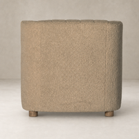 Baldwin Chair in sheepskin camel with a textured, rounded shape and wooden legs.