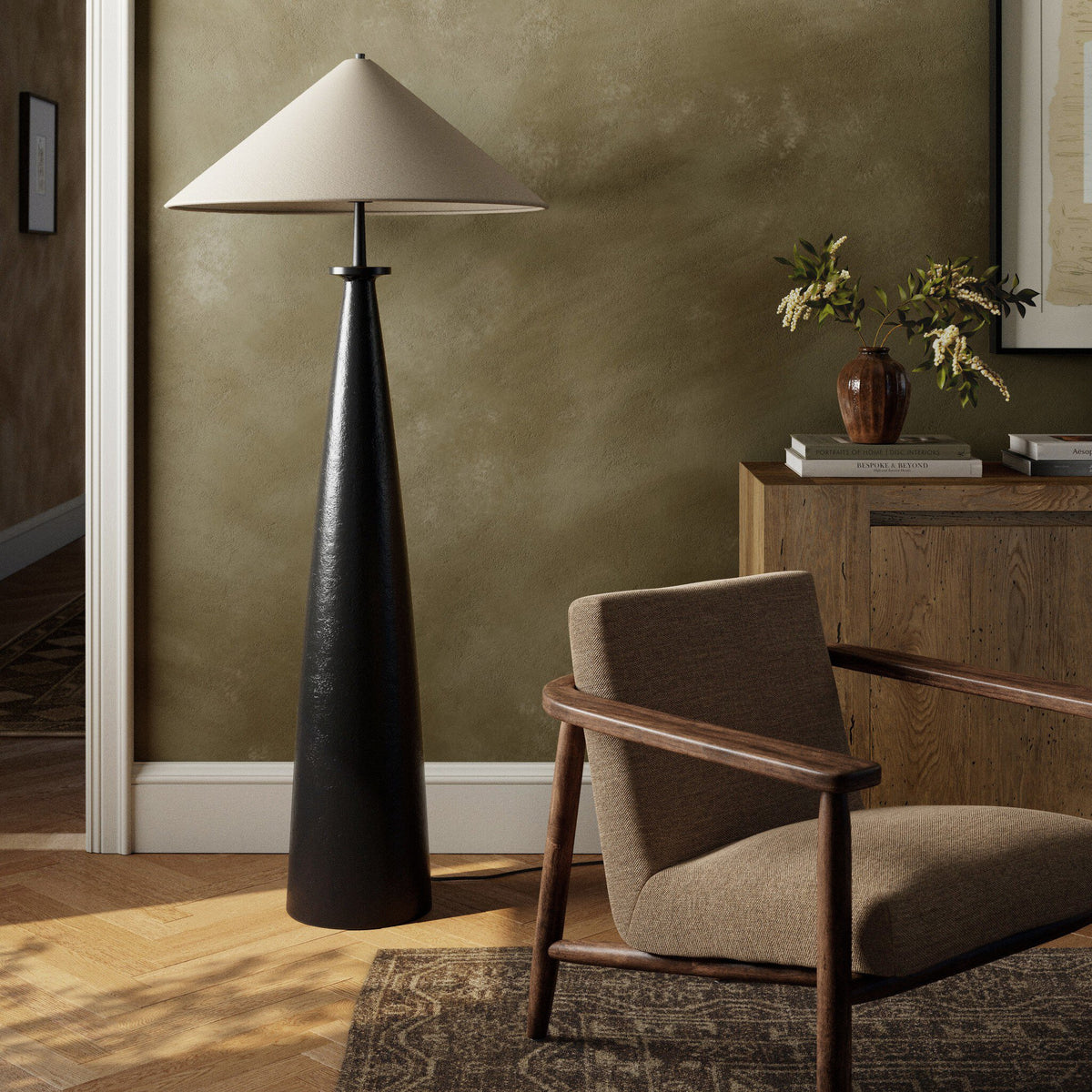 Matte black cast aluminum tapered shade floor lamp in a cozy room setting.