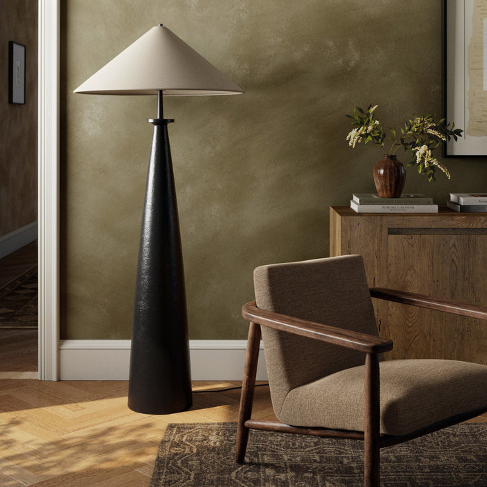Matte black cast aluminum tapered shade floor lamp in a cozy room setting.