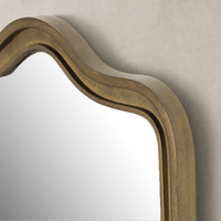 Close-up of the Etta Mirror featuring a wavy Raw Antique Brass Iron frame.