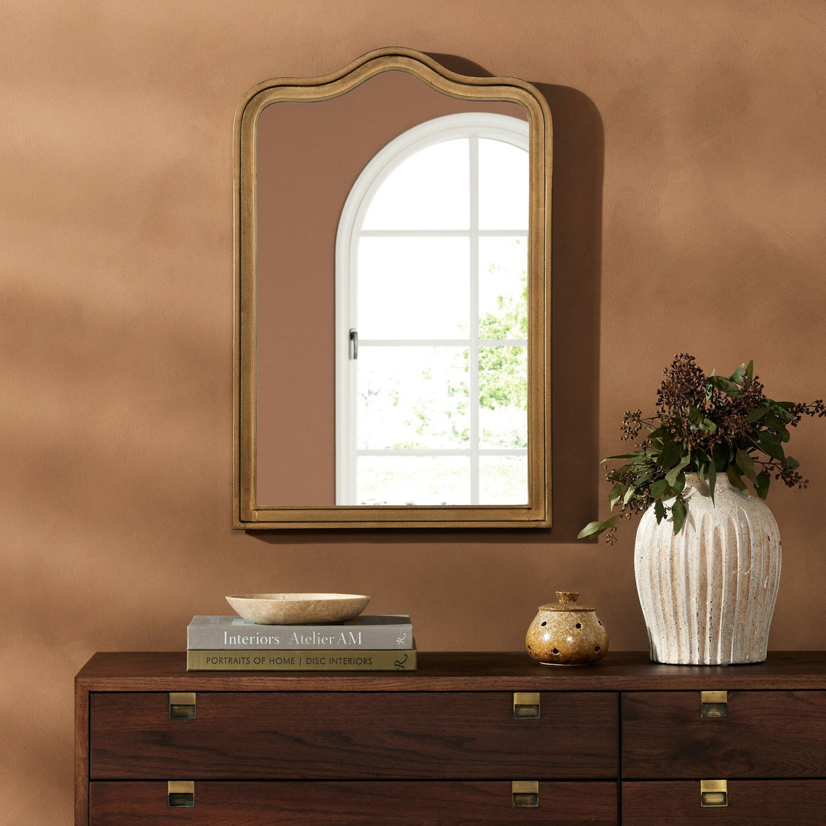 Etta Mirror in raw antique brass iron with a scalloped edge, reflecting natural light.